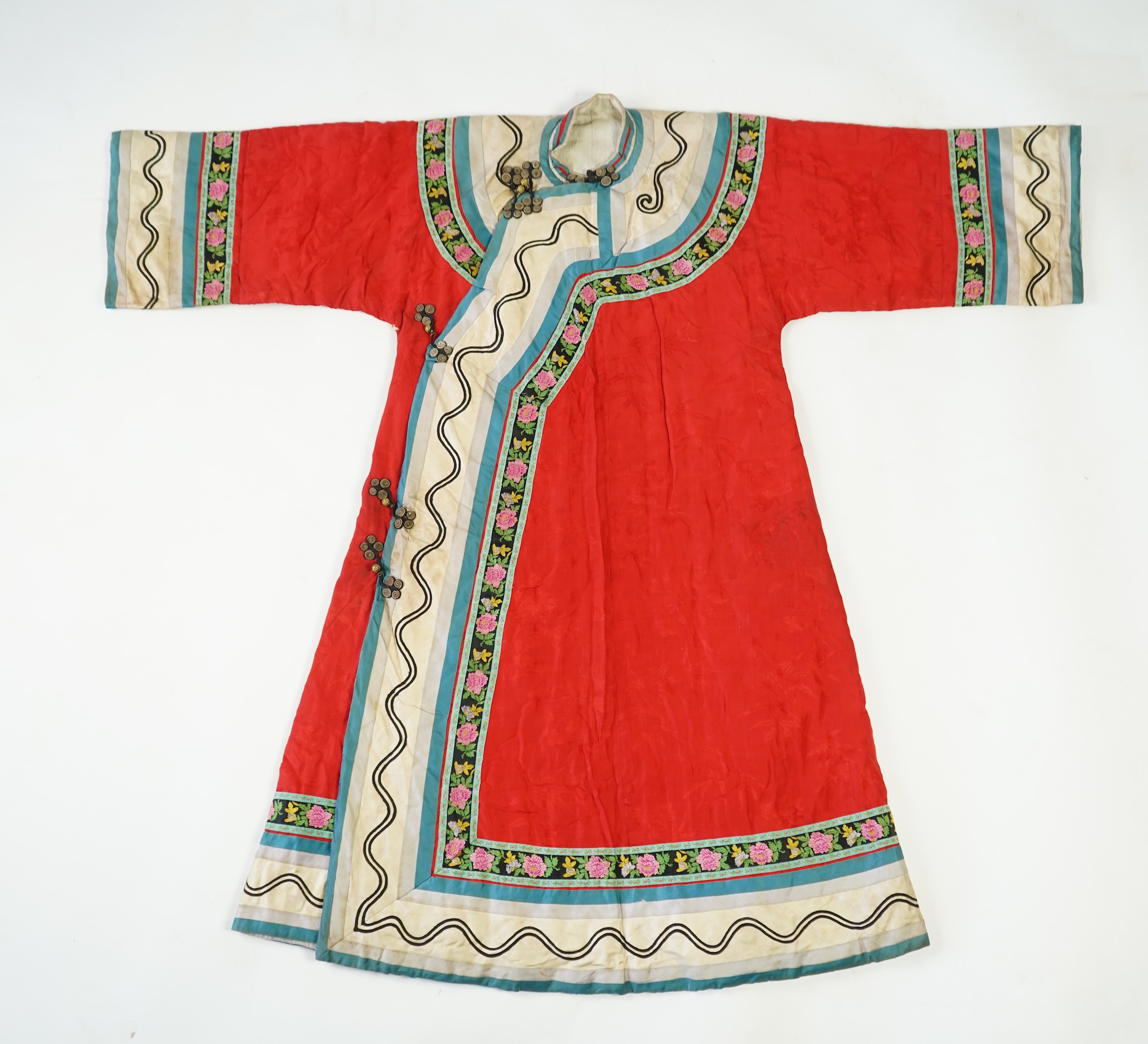 A late 19th century early 20th century Chinese red silk damask quilted Mandarin robe. Decorated with colourful rows braiding and ornate toggling. 116cm long. Condition - minor marks in places, may benefit from specialist